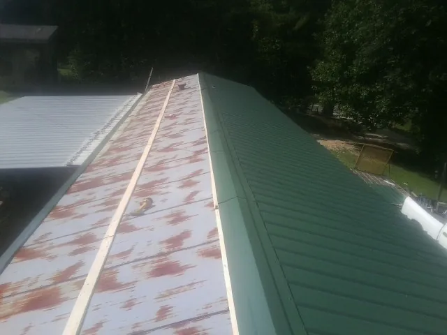 Old rusted panels beside newly installed green metal roofing — Wind Damage Roof Repair by Roofing Brothers in Coldwater